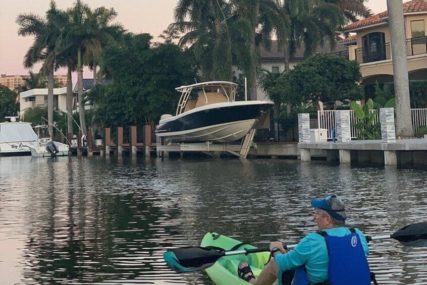 Una persona en kayak sobre aguas tranquilas, una embarcación fondeada cerca y palmeras al fondo. 5