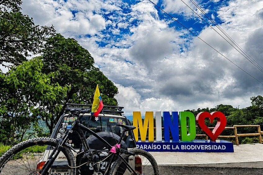 A bicycle with a flag, a sign with 'MIND' and a heart, and a cloudy sky. 2