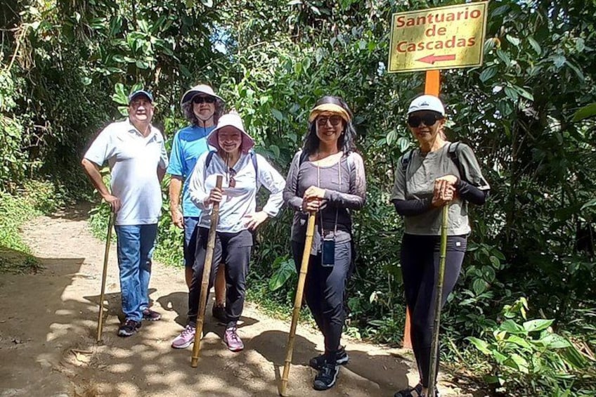 Eine Gruppe von Menschen steht auf einem Feldweg, ein Schild mit der Aufschrift 'Santuario de Cascadas' ist sichtbar. 5