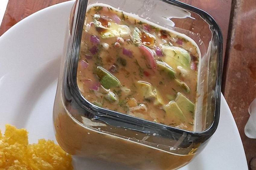 Ein Glasgefäß mit cremiger Gemüsesuppe, serviert mit einer Beilage aus gelbem Mais. 3