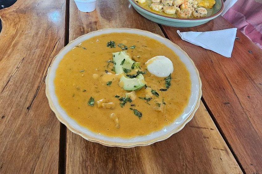 Eine Schüssel Suppe mit Gemüse und einem Klecks Sahne auf einem Holztisch. 2