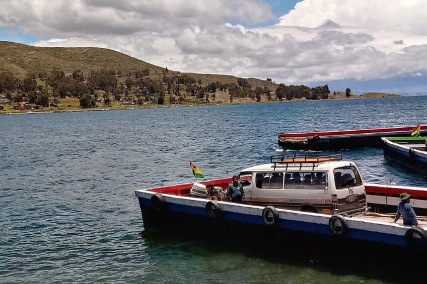 Un lago con barche, un veicolo bianco sul molo e un paesaggio collinare sullo sfondo. 2