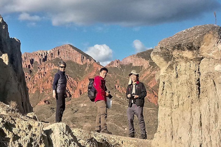Three hikers on a rocky mountain trail with red rock formations in the background. 3