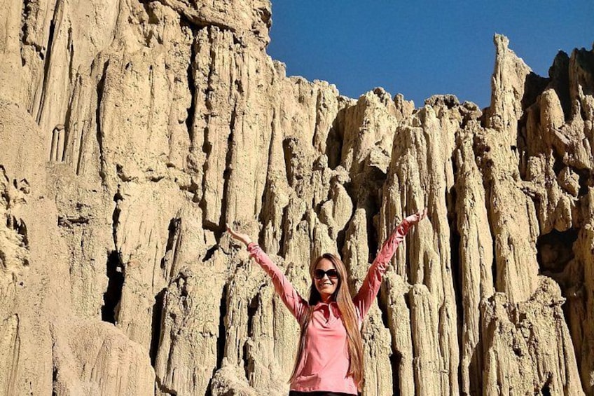 A person standing in front of a rocky cliff with arms raised. 2