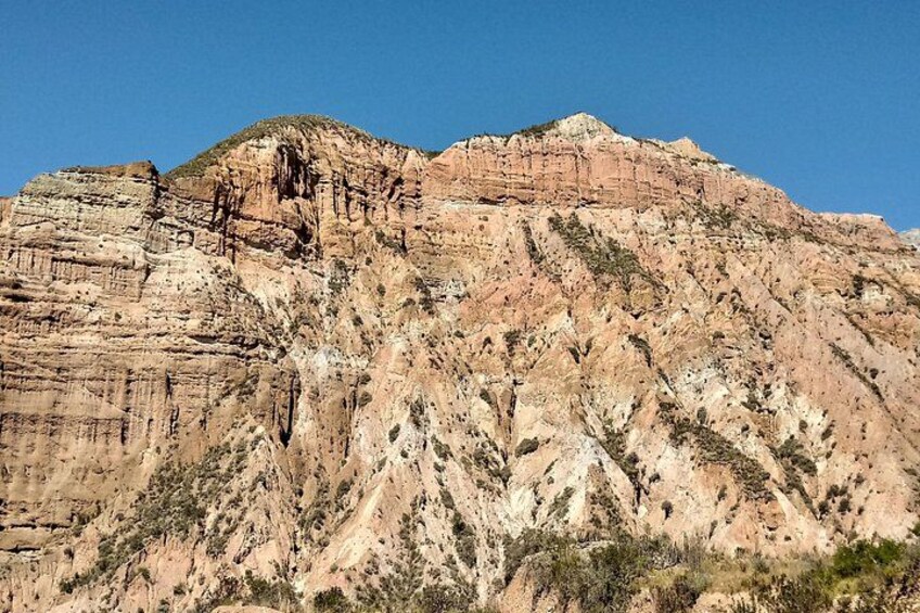 Una montaña escarpada con formaciones rocosas estratificadas y vegetación escasa. 2