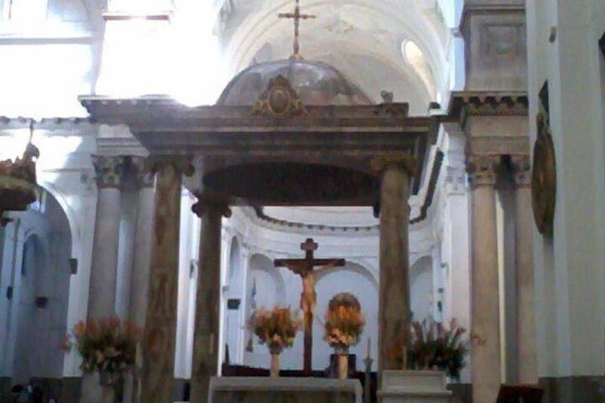 Interno di una chiesa con altare centrale, colonne e composizioni floreali. 3