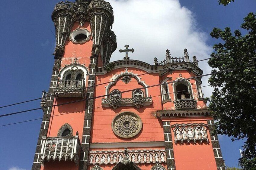 Una chiesa con facciata rossa, balconi decorati e un orologio. 4
