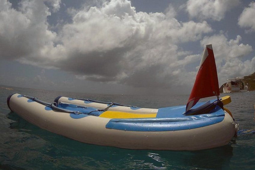Un bote inflable azul y blanco con una vela roja sobre aguas tranquilas. 2