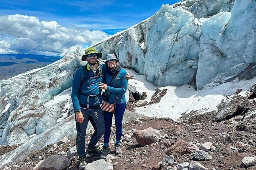 A glacier with two people standing on a rocky terrain. 2