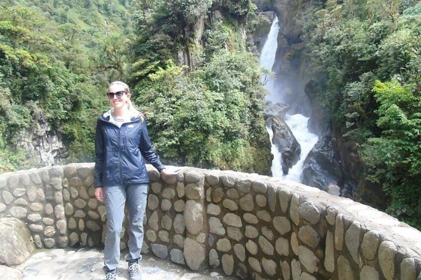 Une personne se tient près d’un mur de pierre, avec une cascade en arrière-plan. 5