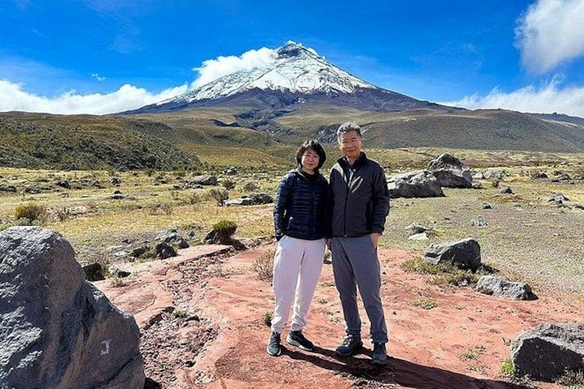 Un couple se tient sur un terrain rocheux, avec une montagne enneigée en arrière-plan. 1