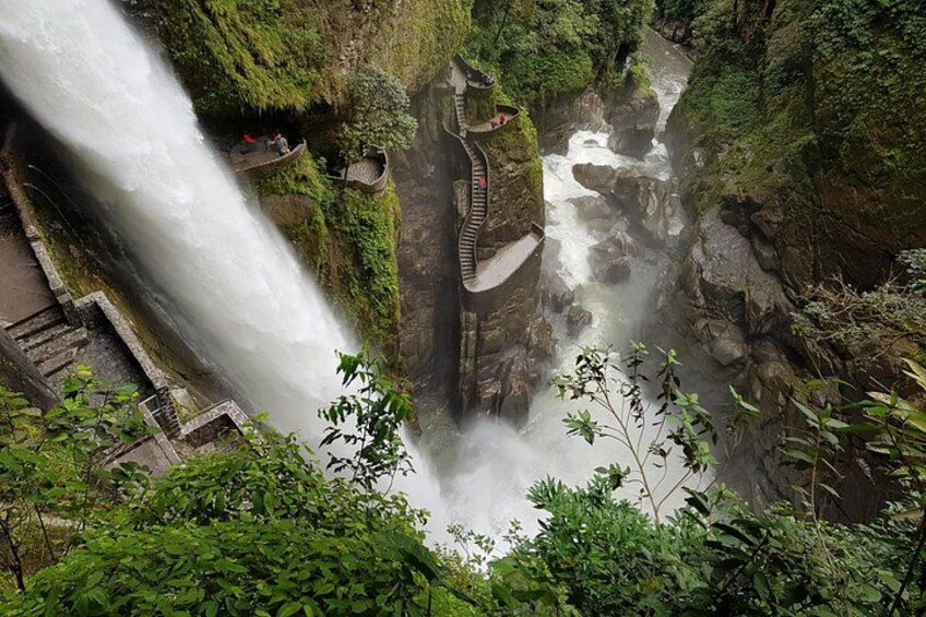 Une cascade se déversant le long d’une falaise rocheuse, entourée d’une végétation luxuriante et bordée d’une passerelle en bois. 3