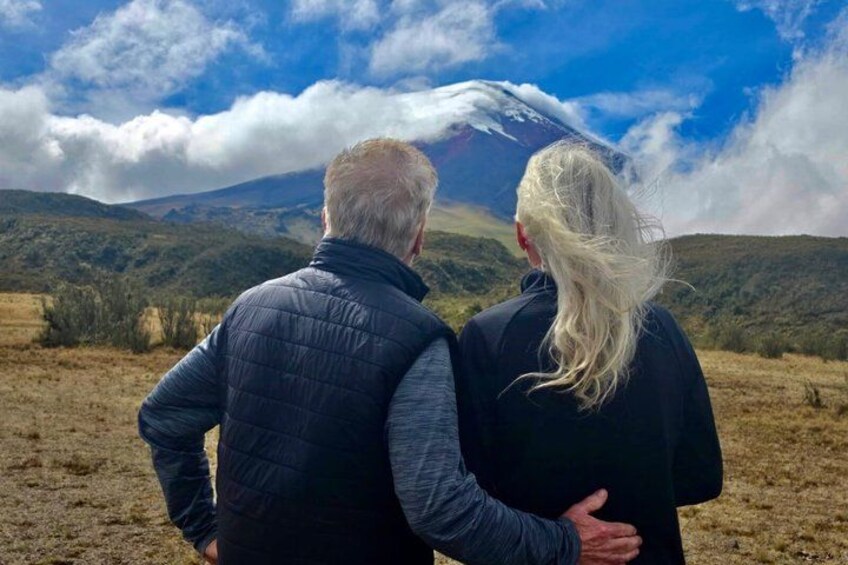 Two people standing on a hill overlooking a mountain with a snow-capped peak. 2