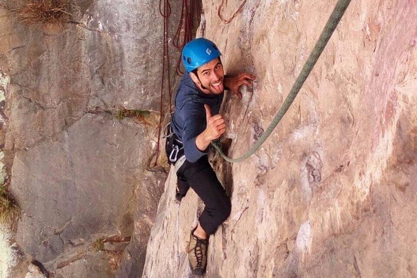 Una persona escalando una pared rocosa con una cuerda. 2
