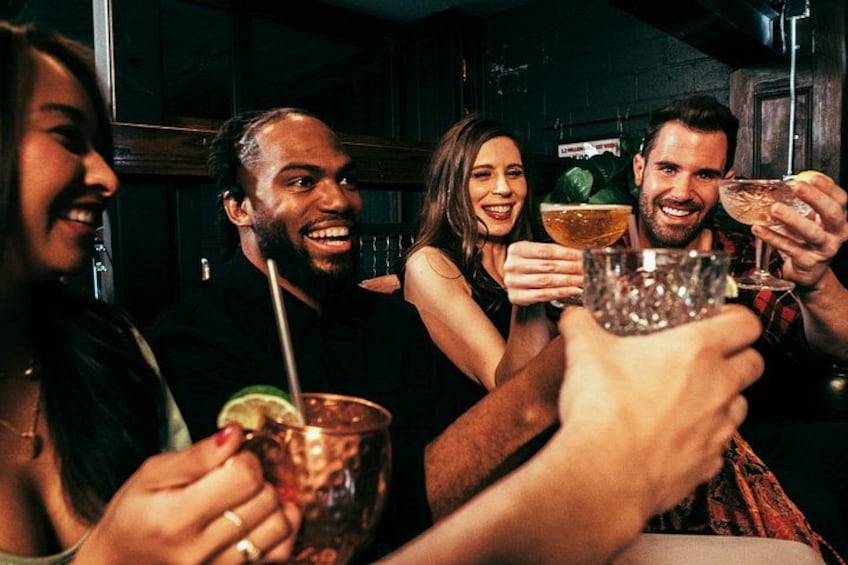 A group of people toasting with drinks in a dimly lit bar. 3