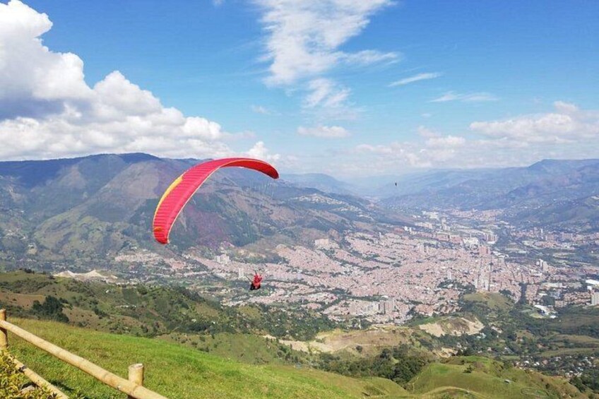 Una persona fa parapendio sopra una città con montagne sullo sfondo. 5