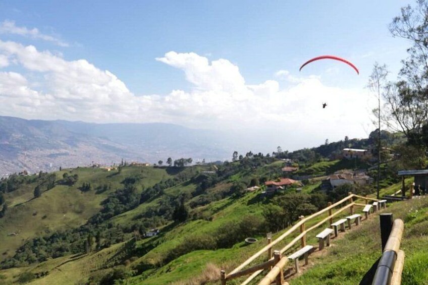 Una persona pratica parapendio sopra un paesaggio collinare sotto un cielo sereno. 4
