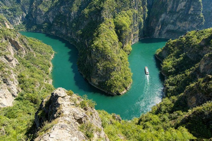 Ein Fluss schlängelt sich durch eine Schlucht mit steilen Klippen und dichtem Grün. 1