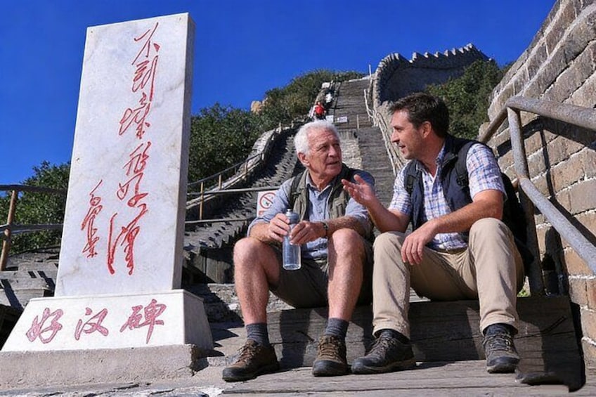 Zwei Personen sitzen auf Stufen, im Hintergrund ein Steinmonument. 3