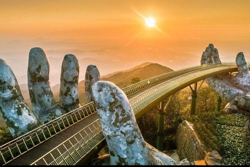 Un puente de diseño singular, sostenido por grandes formaciones rocosas, con un atardecer al fondo. 5