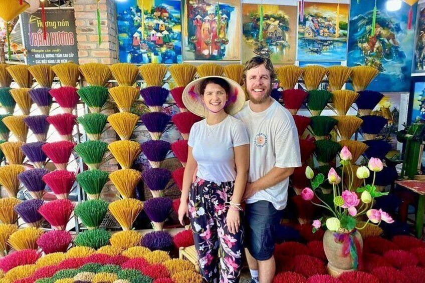 A person standing in front of a wall of colorful fans, with a vase of flowers on the floor. 5