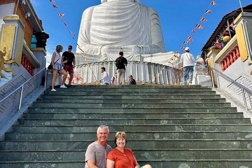 A large white statue at the top of a staircase with people ascending and descending. 2
