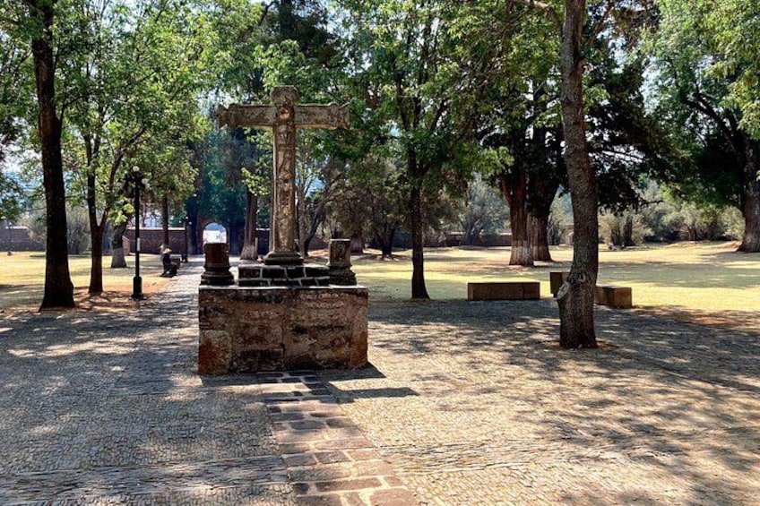 Un cimitero con una croce imponente, alberi e panchine in pietra. 4