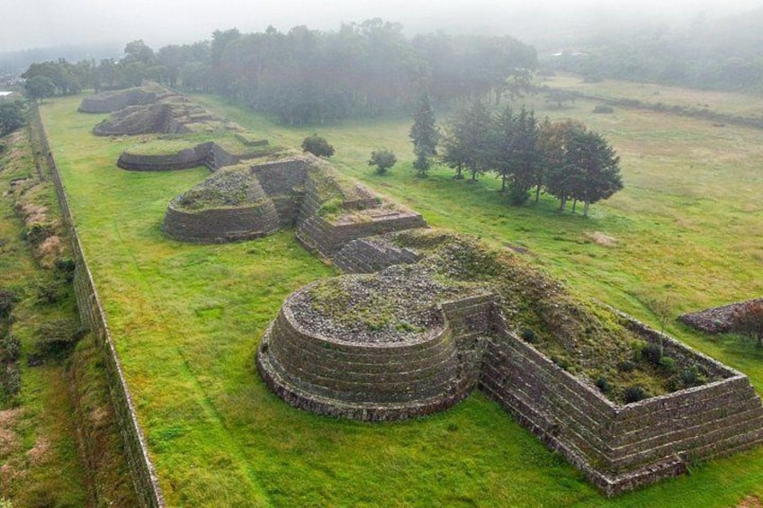 Antiche strutture di pietra circolari in un prato erboso. 1