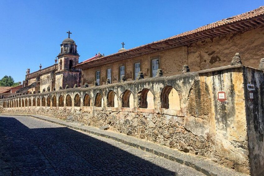 Un muro di pietra storico con archi e una chiesa con un campanile. 3