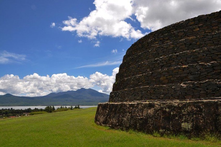 Un muro di pietra, un prato erboso e montagne sullo sfondo. 5