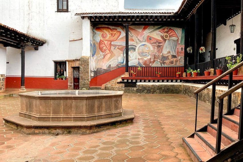 Une cour avec une fontaine, une fresque murale et un escalier. 2