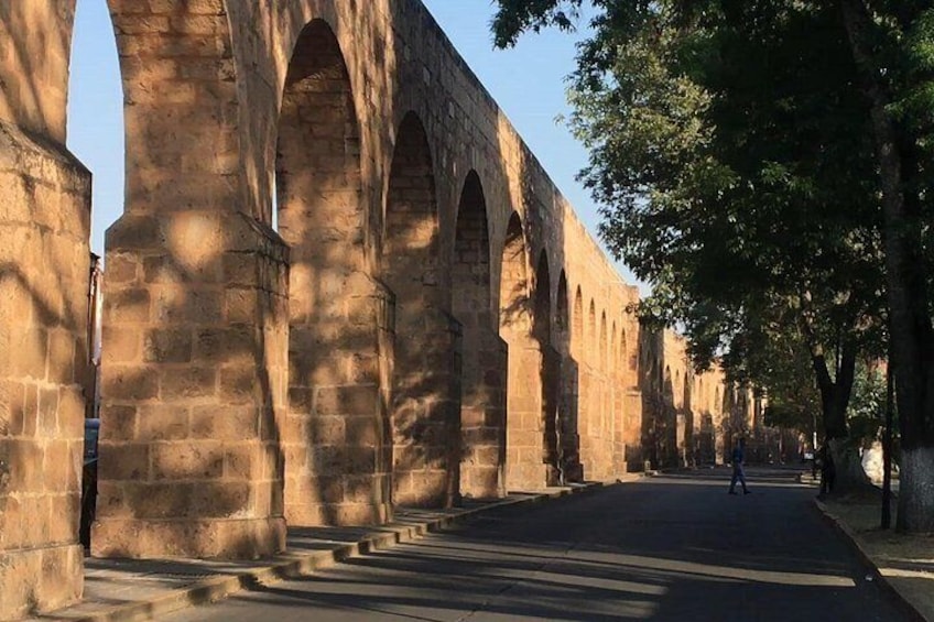 A stone bridge with multiple arches, a paved road, and trees lining the pathway. 5