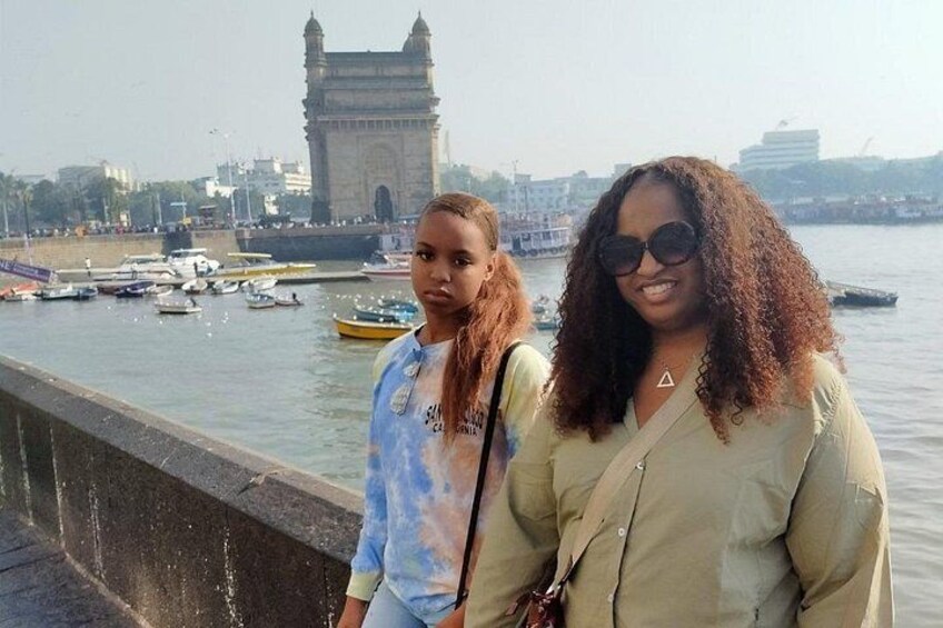 Two people standing by a waterfront with a large tower in the background. 3