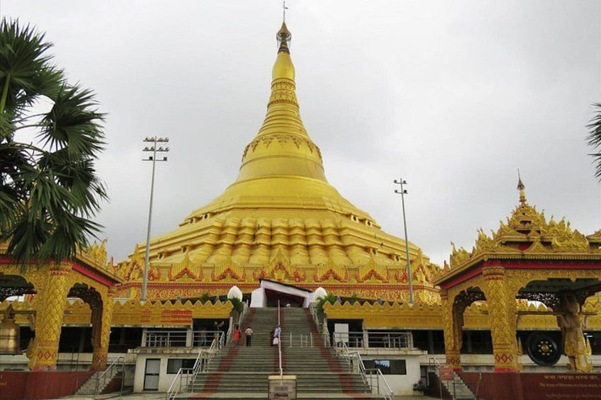 En stor, gylden stupa med trapper op til den, omgivet af dekorative bygninger. 1