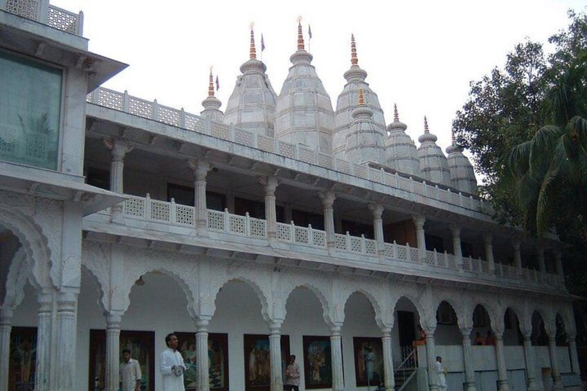 A white temple with multiple domes and a balcony. 5
