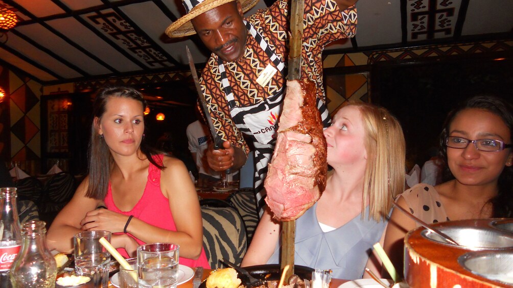 man serving meat at table in africa