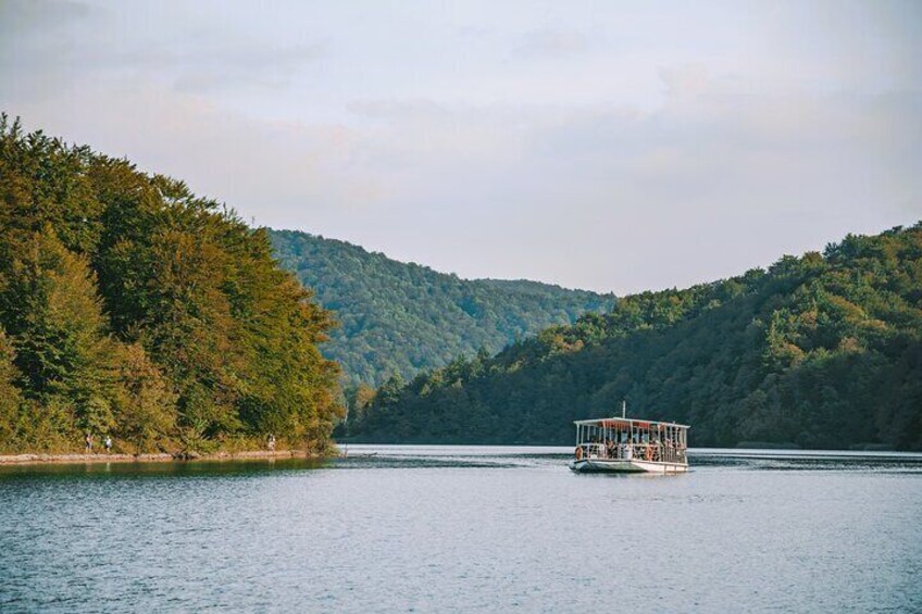 A boat on a calm lake surrounded by forested hills. 4