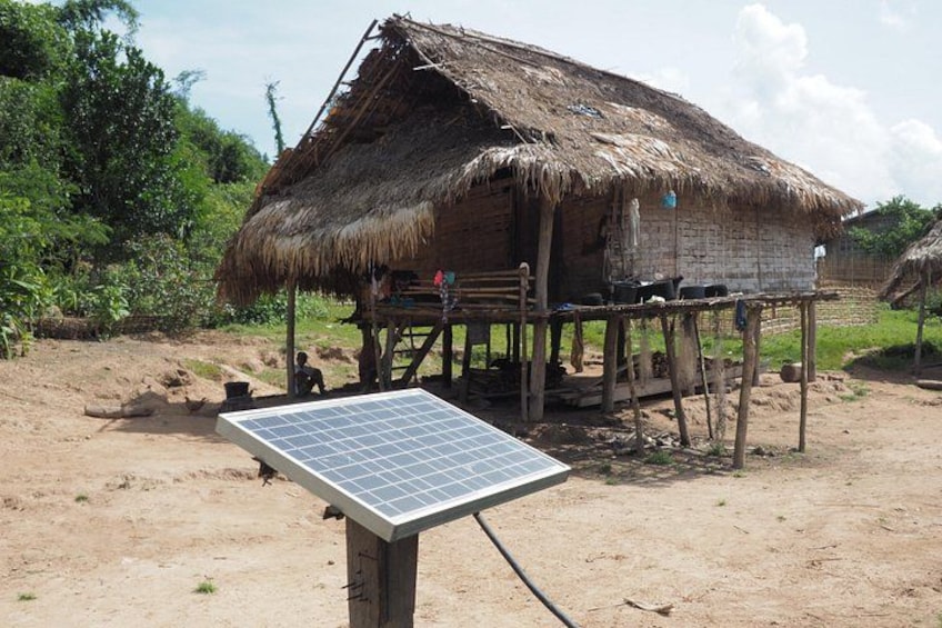 Eine strohgedeckte Hütte mit einer Solaranlage davor. 1