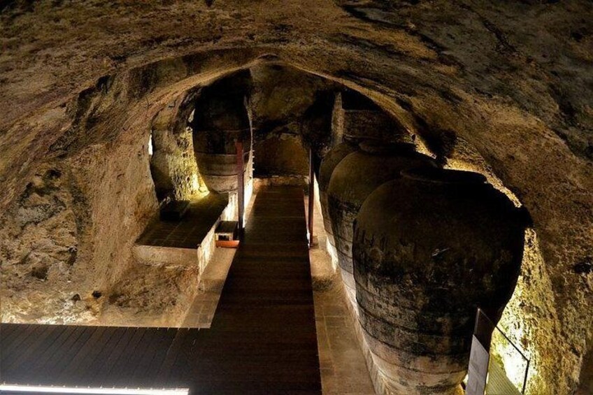 Un túnel de piedra con un pasillo de madera y una gran estructura pétrea a la derecha. 4