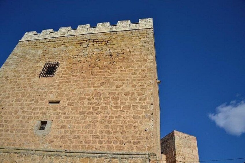 Una alta torre de piedra con almenas en la parte superior y una pequeña ventana cerca de la base. 5