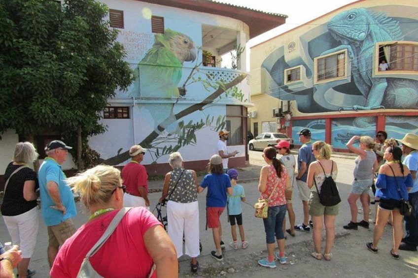 A mural of a parrot and a snake on a building, with people gathered around it. 1
