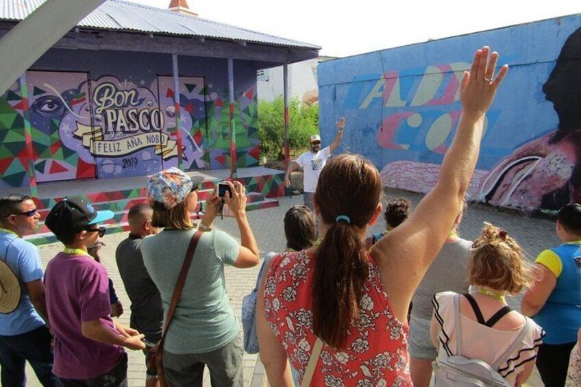 Une foule de personnes se trouve à un événement en plein air, les murs étant décorés de peintures murales colorées. 1