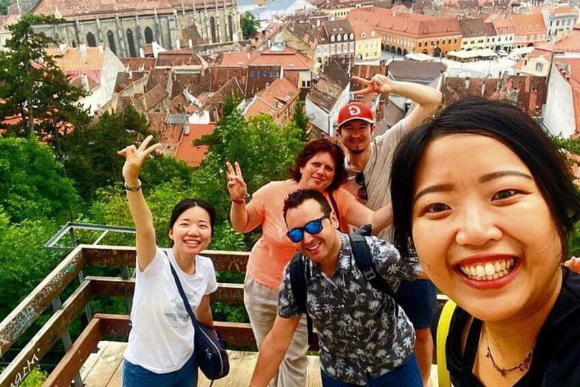 A group of people on a wooden staircase with a cityscape in the background. 3