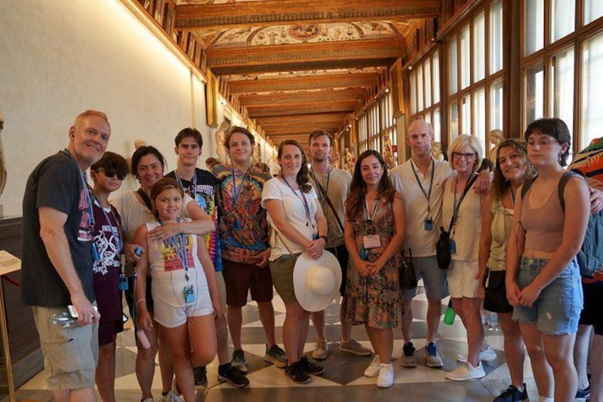 A group of people in a hallway with wooden ceilings and large windows. 4