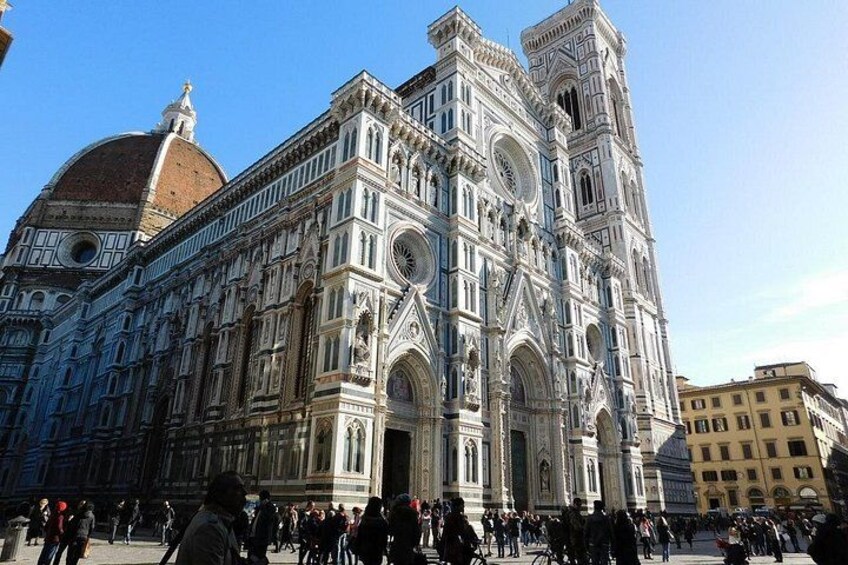 A historic cathedral with intricate architecture, a dome, and a crowd of people. 3