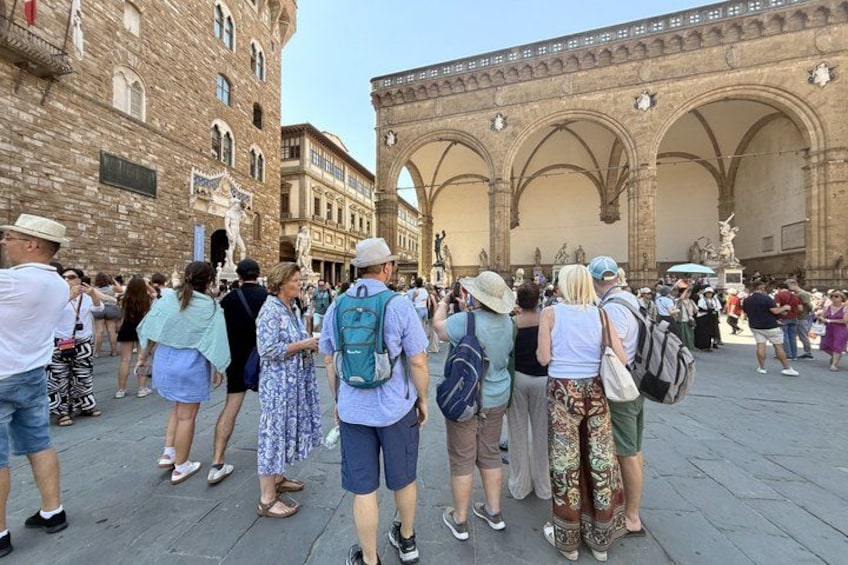 A crowded square with historic buildings and arches. 2