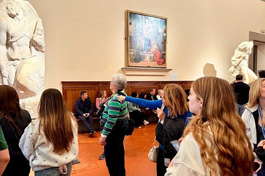 A group of people in a museum, observing a painting and sculptures. 2