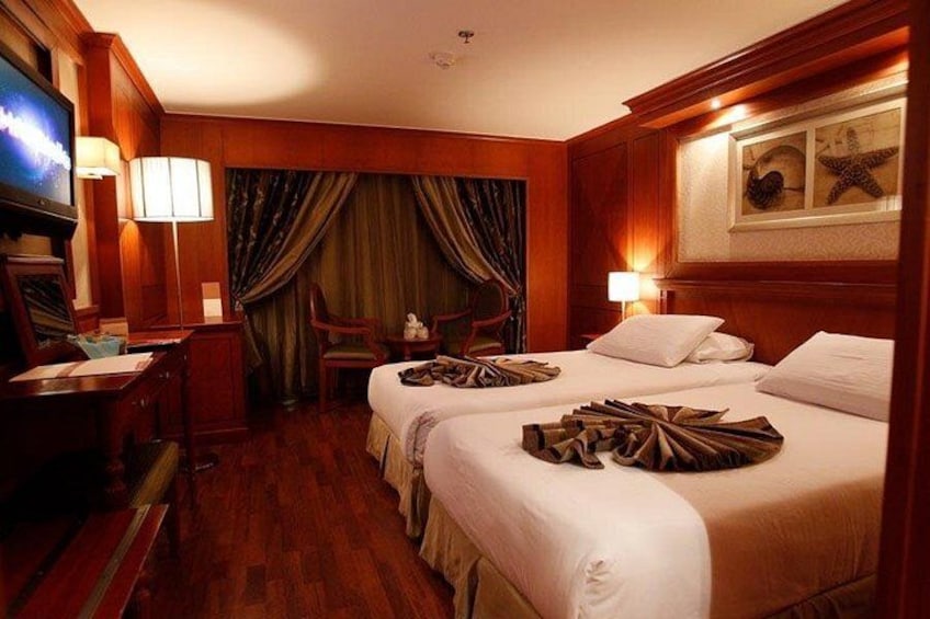 A hotel room with two beds, a desk, a television, and a curtain. 2