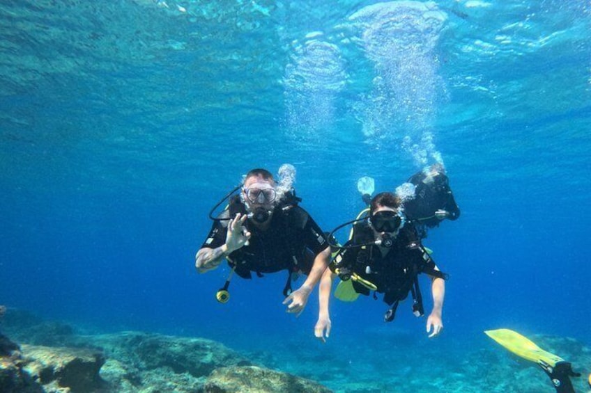 Two scuba divers underwater with fins and tanks. 1