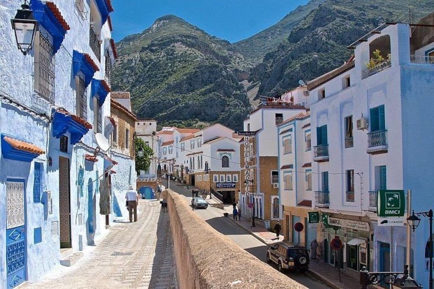 Una calle estrecha bordeada de edificios, una montaña al fondo y un cielo despejado. 1